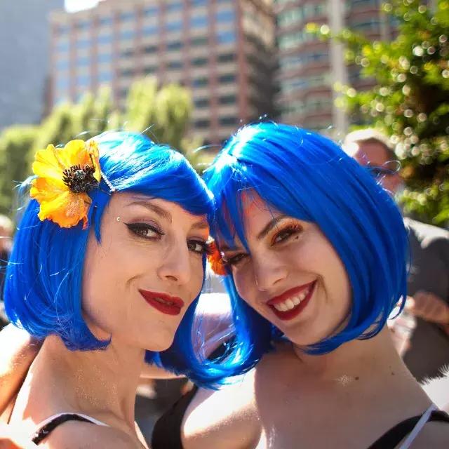 Two women sporting blue wigs attend San Francisco Pride.